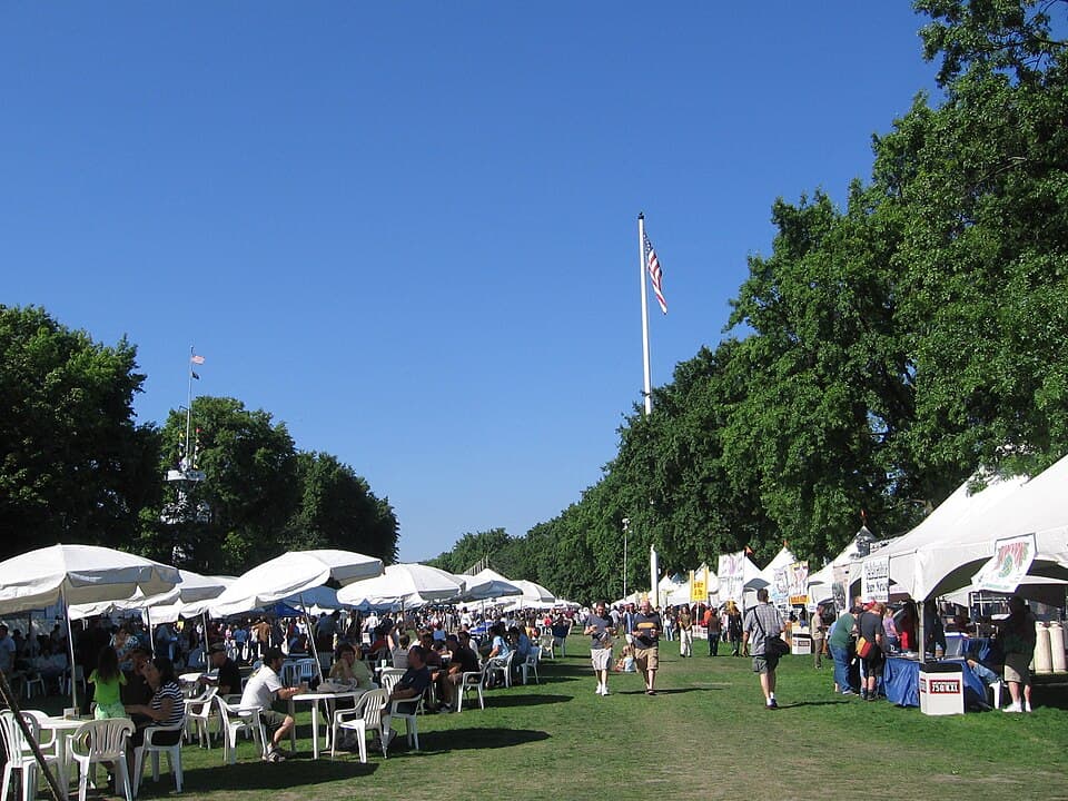 Rows of white festival tents on a sunny lawn packed with beer festival crowds